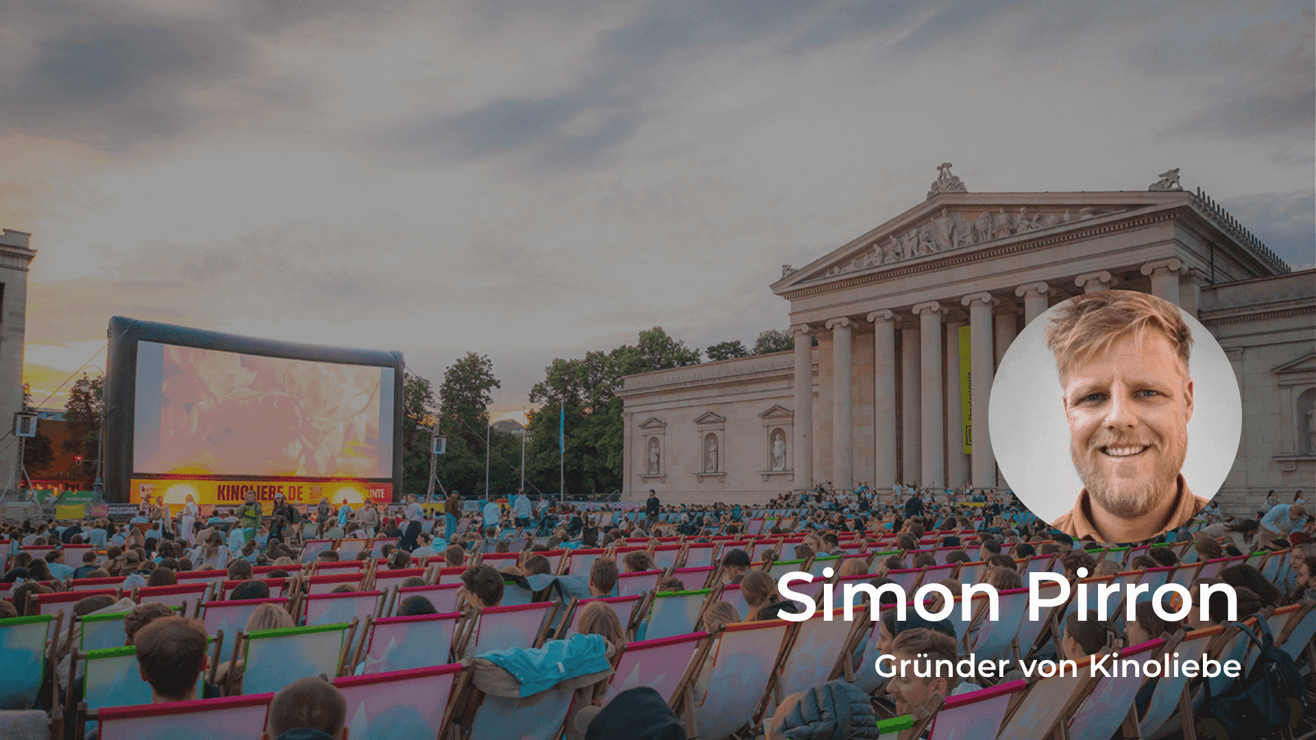 Outdoor cinema with a large audience, a classical building, and a portrait of Simon Pirron.
