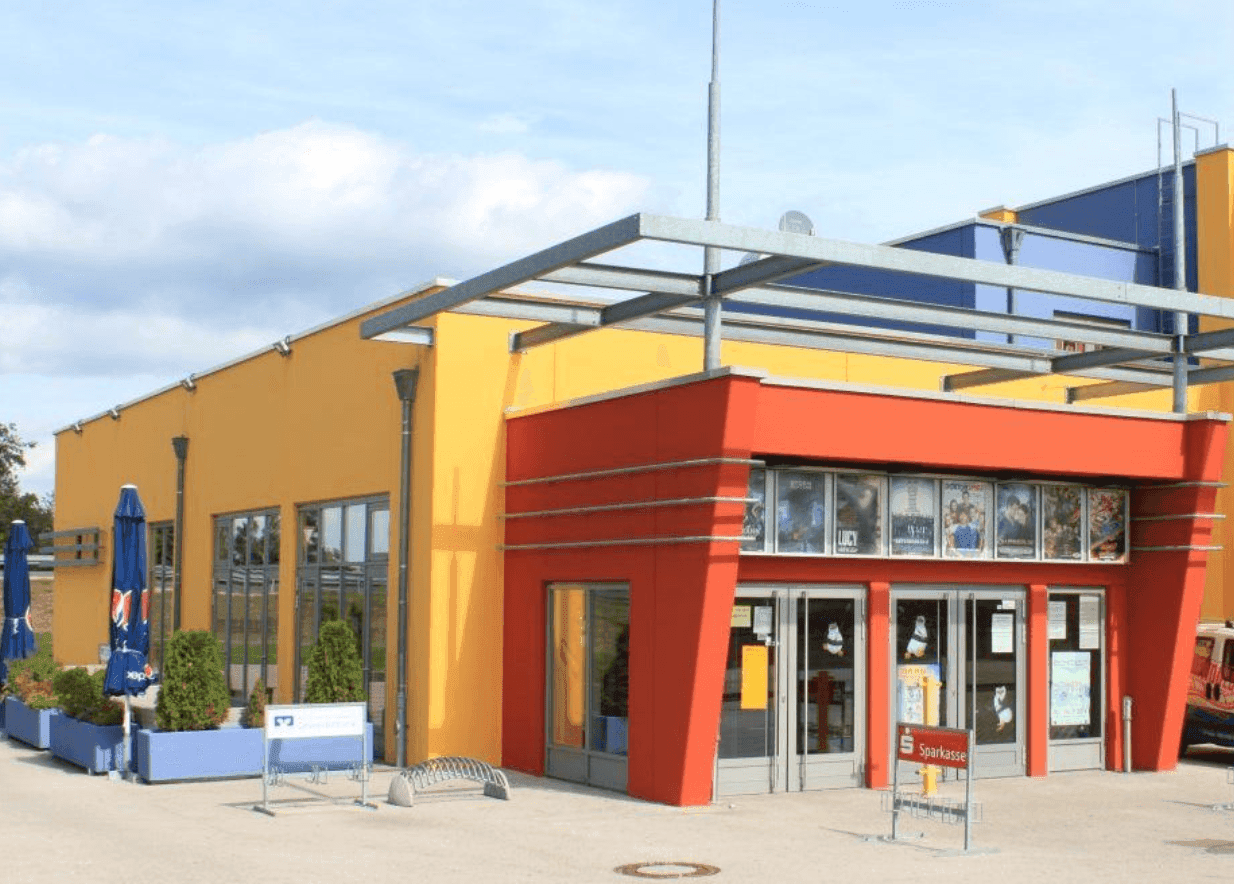 Bright yellow and red modern building featuring a prominent entrance and outdoor dining area.